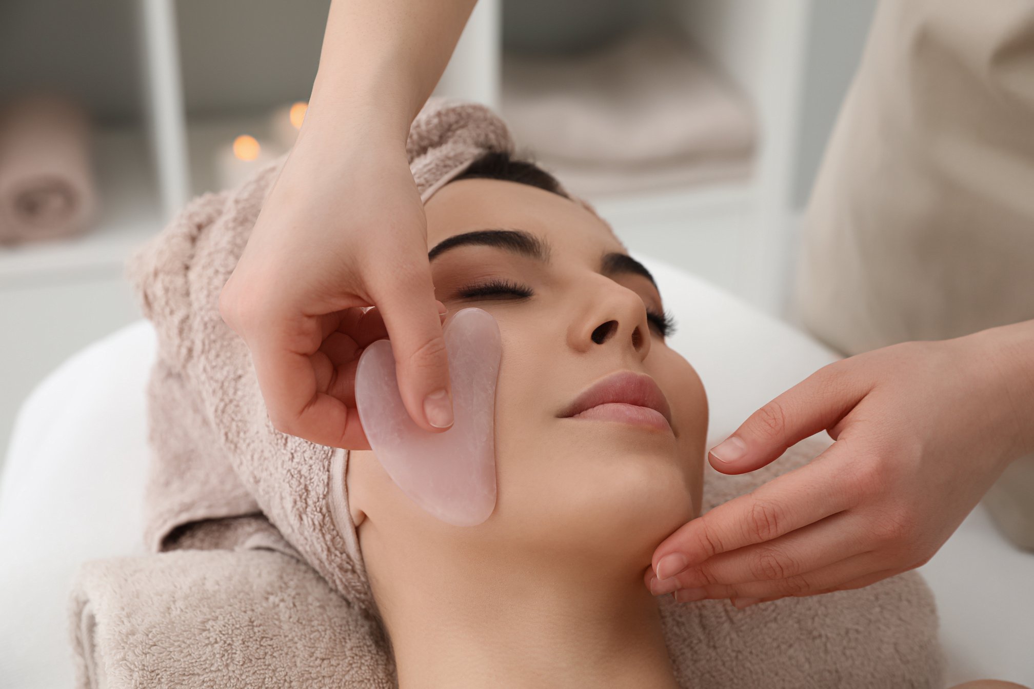 Young Woman Receiving Facial Massage with Gua Sha Tool in Beauty