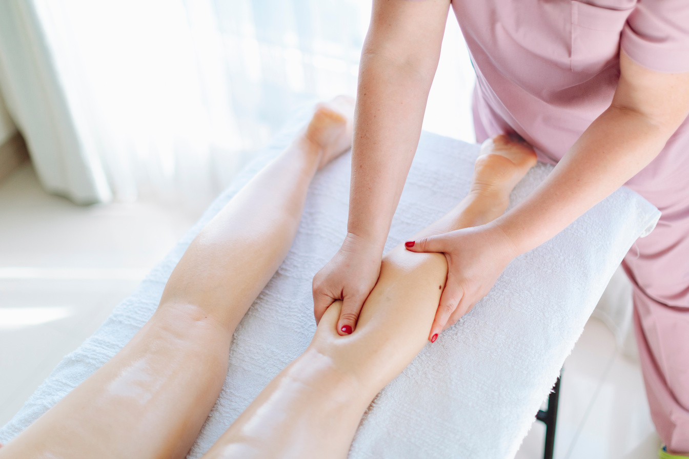 Massage therapist at beauty salon making anti-cellulite massage. Body, leg and foot massage and lymphatic drainage